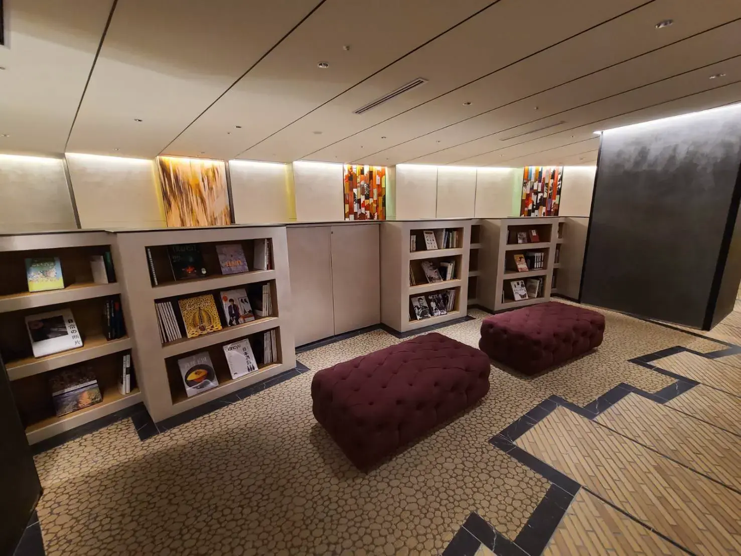 落ち着いた色合いの読書スペース、モダンなデザインの棚と快適な座席