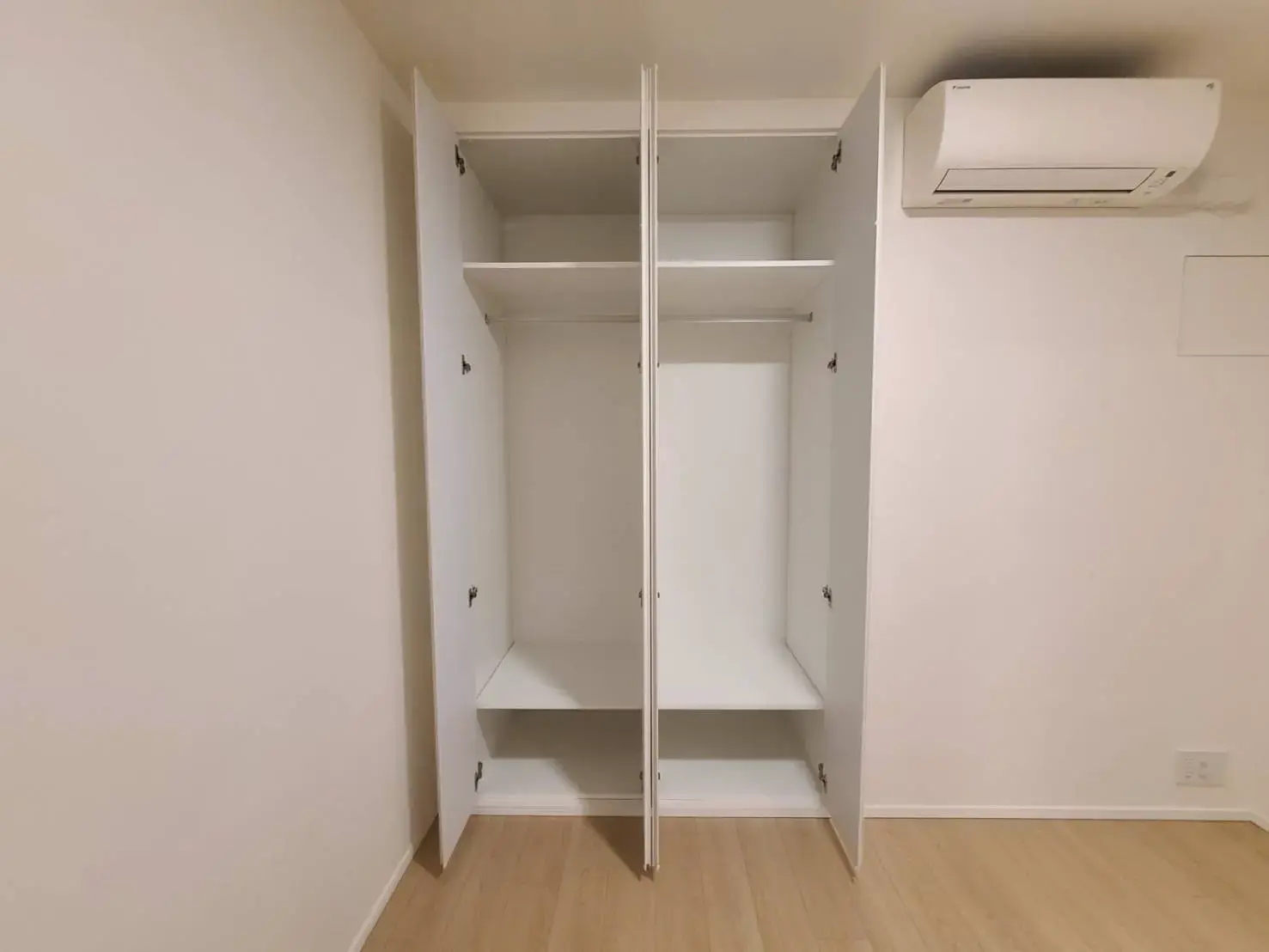 壁埋め込みのクローゼットとエアコンが付いているシンプルな部屋