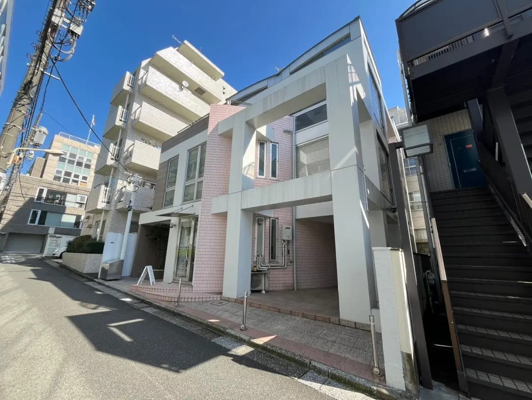 都市部に位置するモダンな外観の住宅街、晴天の下での明るい通り、ピンクのタイルが特徴的な建物
