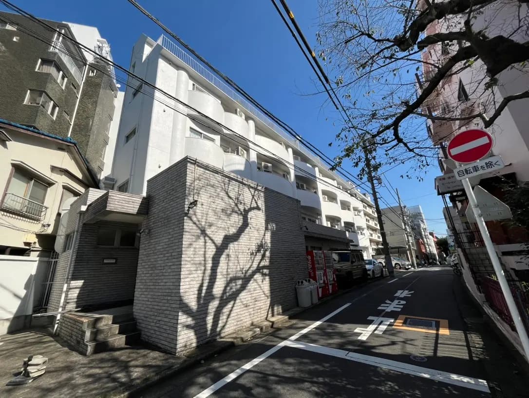青空の下、木々の影が映る都市のアパートメント建物、日本の住宅街の風景