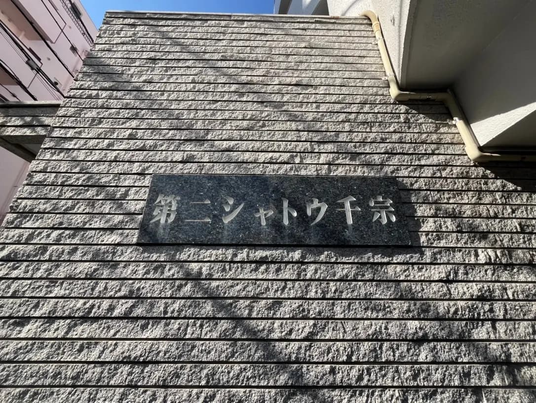 建物の壁に取り付けられた石材のプレート、日本語で「新シネマ」と刻まれ、日差しを浴びる外観