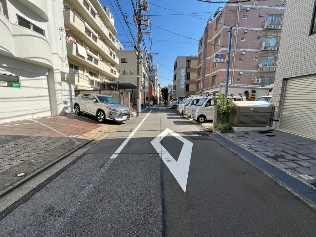 晴れた日の日本の住宅街の風景、建物と駐車している車、街路樹と青空
