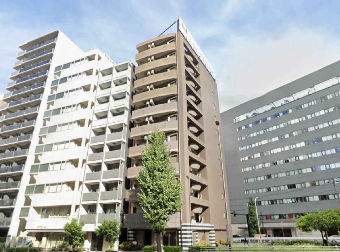 - 都市の中に佇む高層マンション、洗練された外観と緑豊かな庭が調和する景観