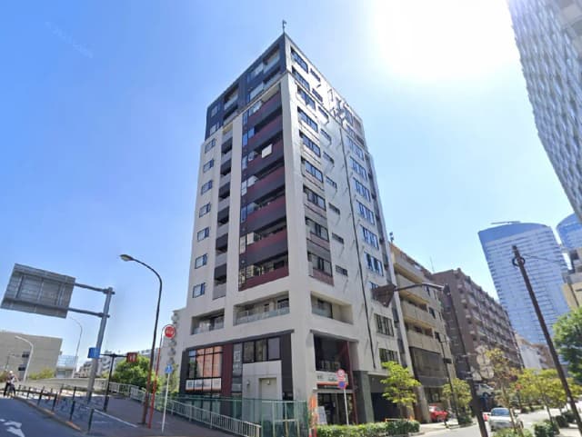 - 周辺のビルに囲まれた現代的な外観の高層マンション、晴れた青空の下で撮影された画像