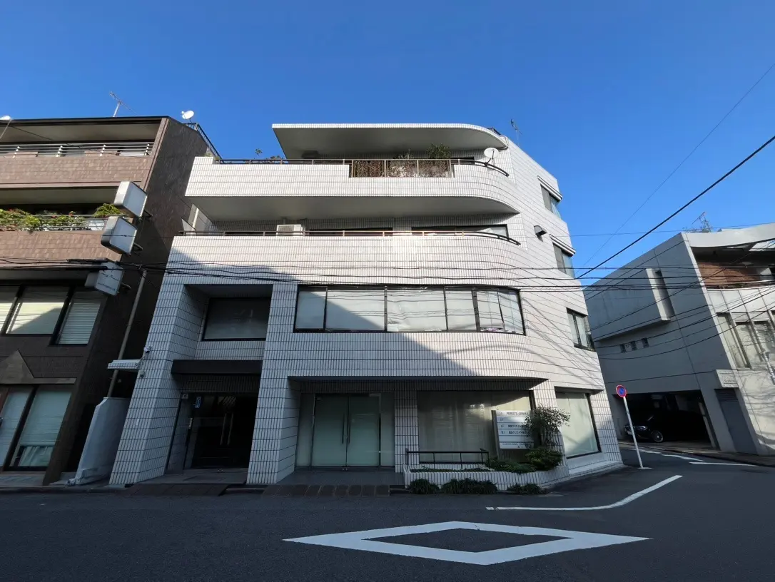 都会の角に位置する現代的なデザインのマンション、晴天の下で明るく撮影