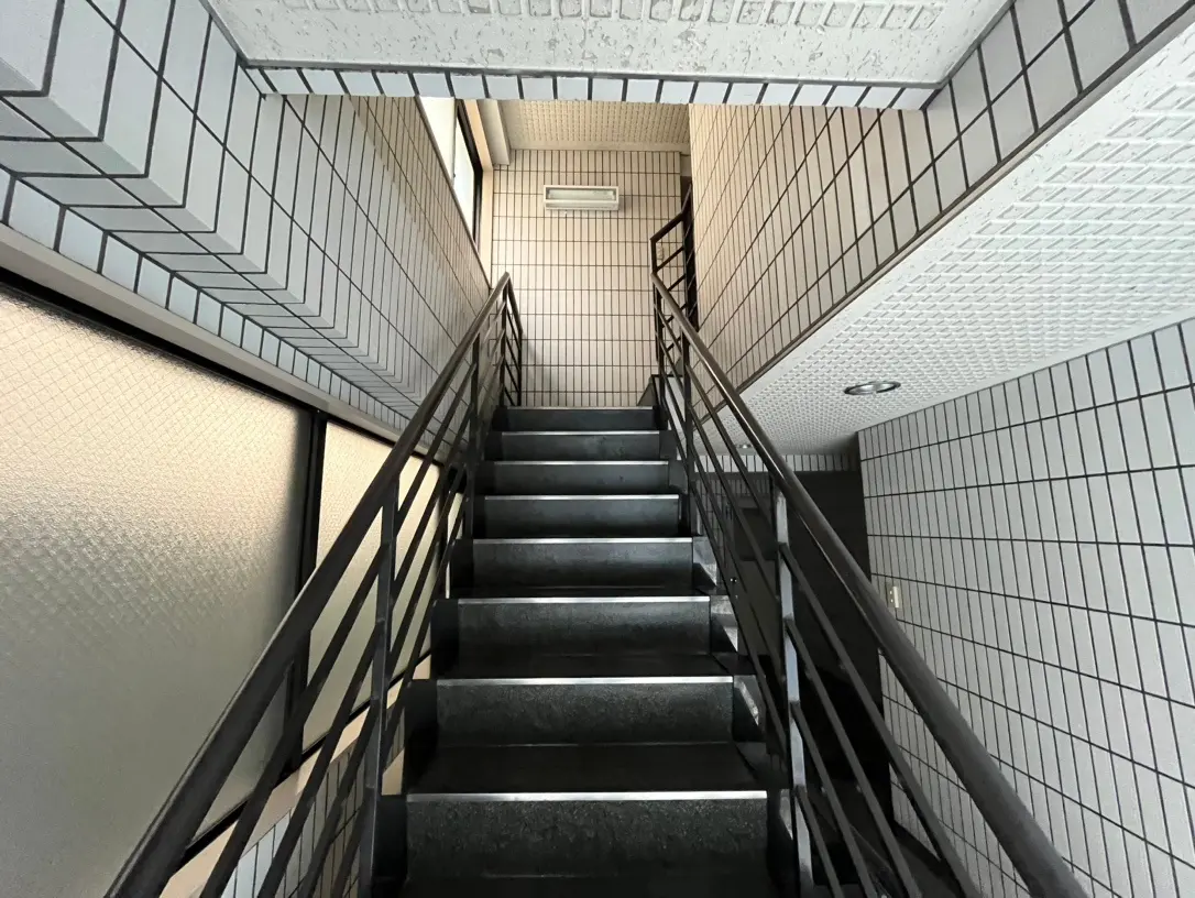モノトーンのタイル張りが特徴的な階段、モダンなデザインの照明と手すり