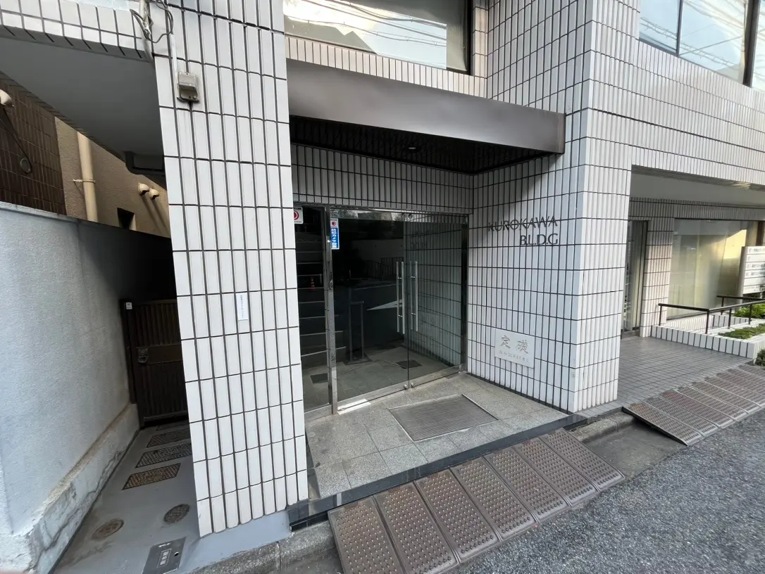 都会のオフィスビルの入り口、タイル張りのファサード、アクセスランプとガラス扉