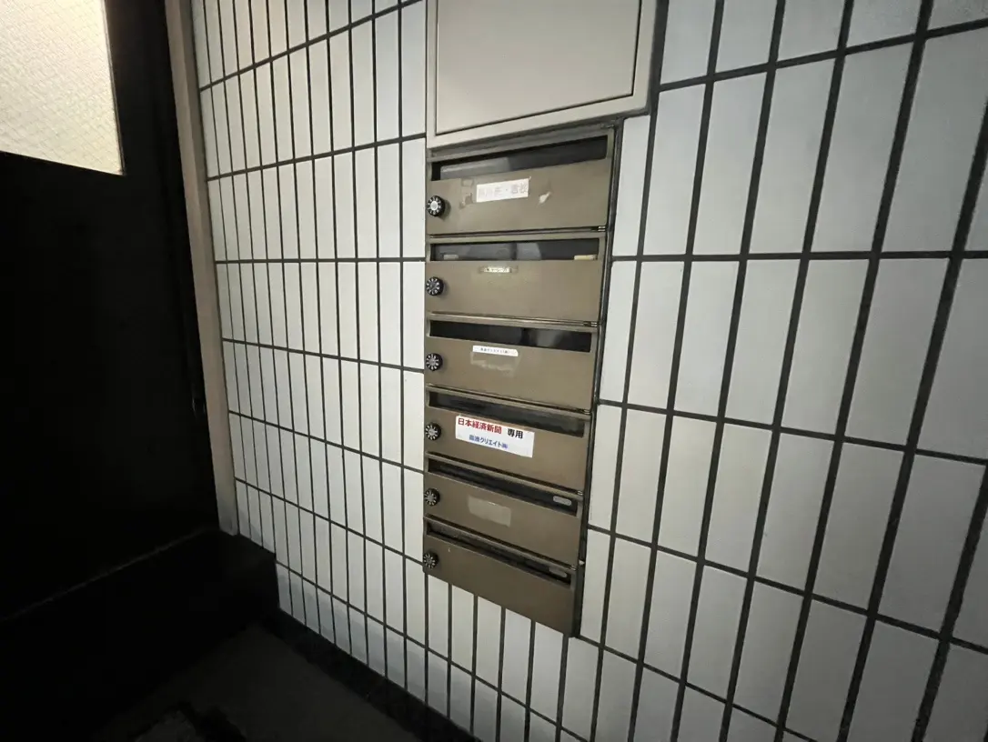 日本のマンションのエントランスにある郵便ポスト、隣に和紙風の照明と格子模様の壁