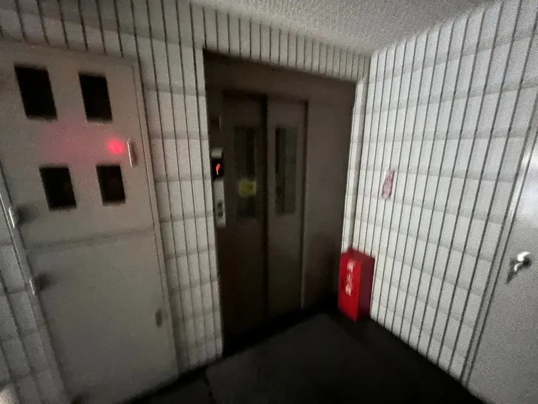 暗い照明のビルのエントランス、タイル壁、非常用設備、自動ドア