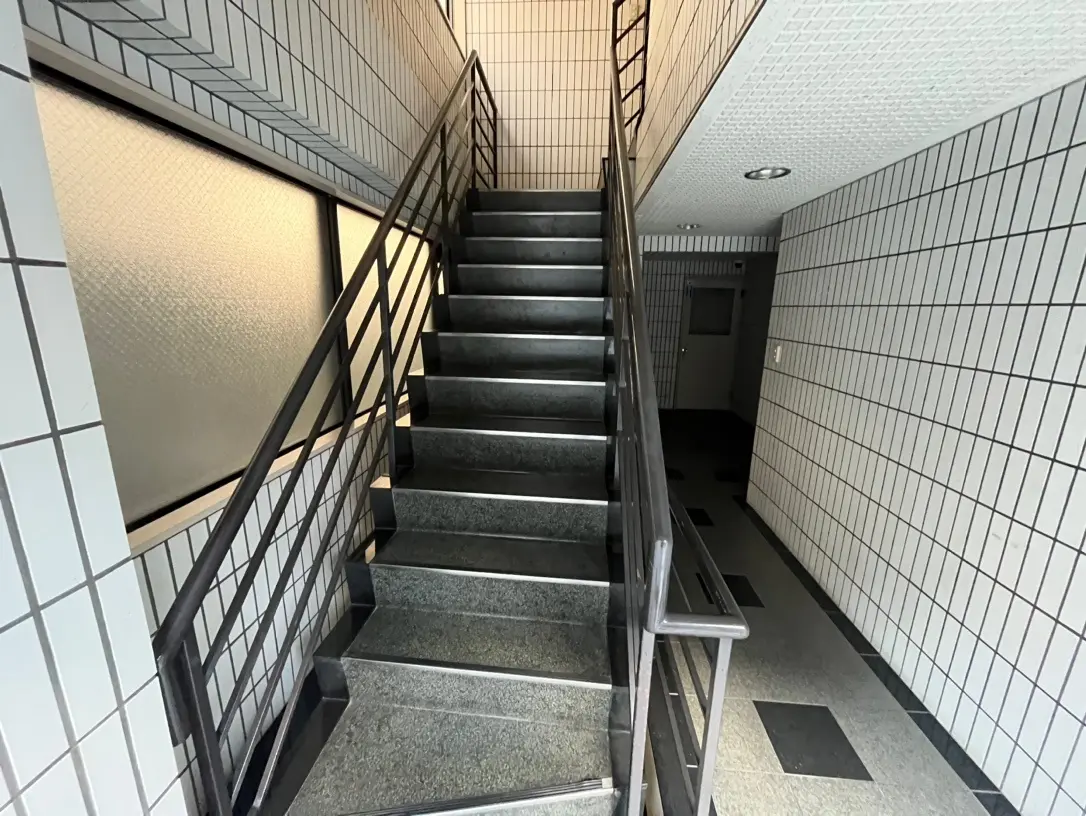 モダンなデザインの階段、白いタイル壁、黒にアクセントのあるフローリング