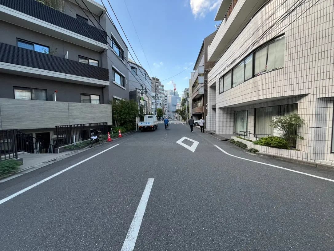 都会の静かな住宅街の道路、現代的な建物と歩行者、晴れた日の風景