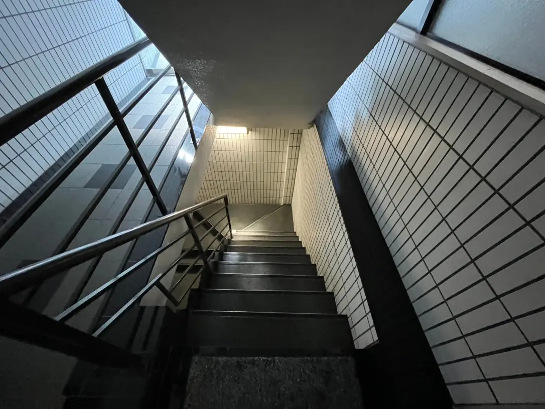 照明のあるモダンな建物の階段、白いタイル壁、黒い手すり