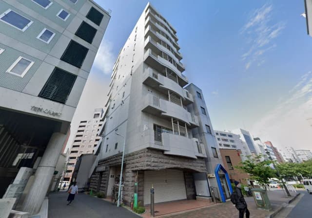 - 都市型のモダンな建物、十字路に面し、2階以上のバルコニーと洗練された外観を持つビルの外観。