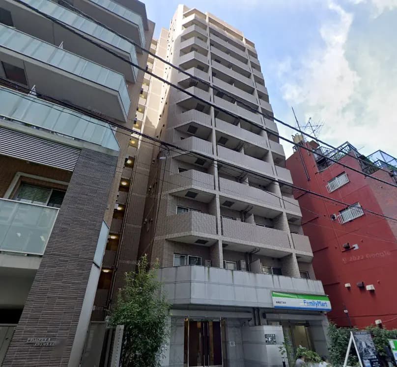 - 都市的なアパートメントビル、近隣にファミリーマートがあり、周辺の建物と空が見える風景