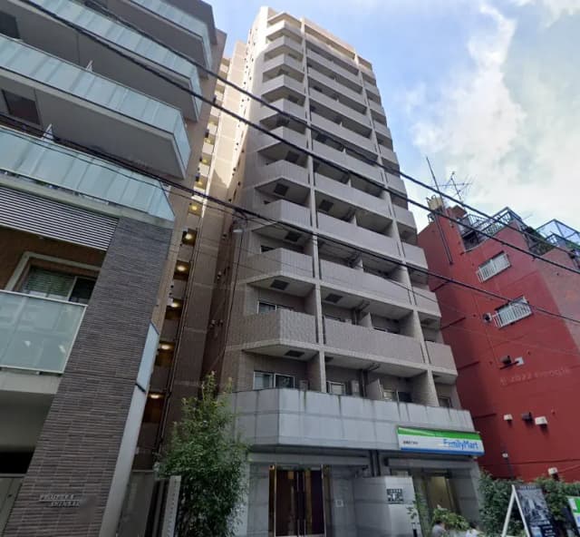 - 都市的なアパートメントビル、近隣にファミリーマートがあり、周辺の建物と空が見える風景