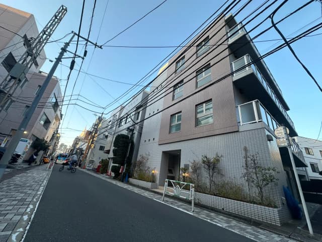 日本の住宅街の風景、多くの電線が交差する青空、アスファルトの道路と近代的な建物