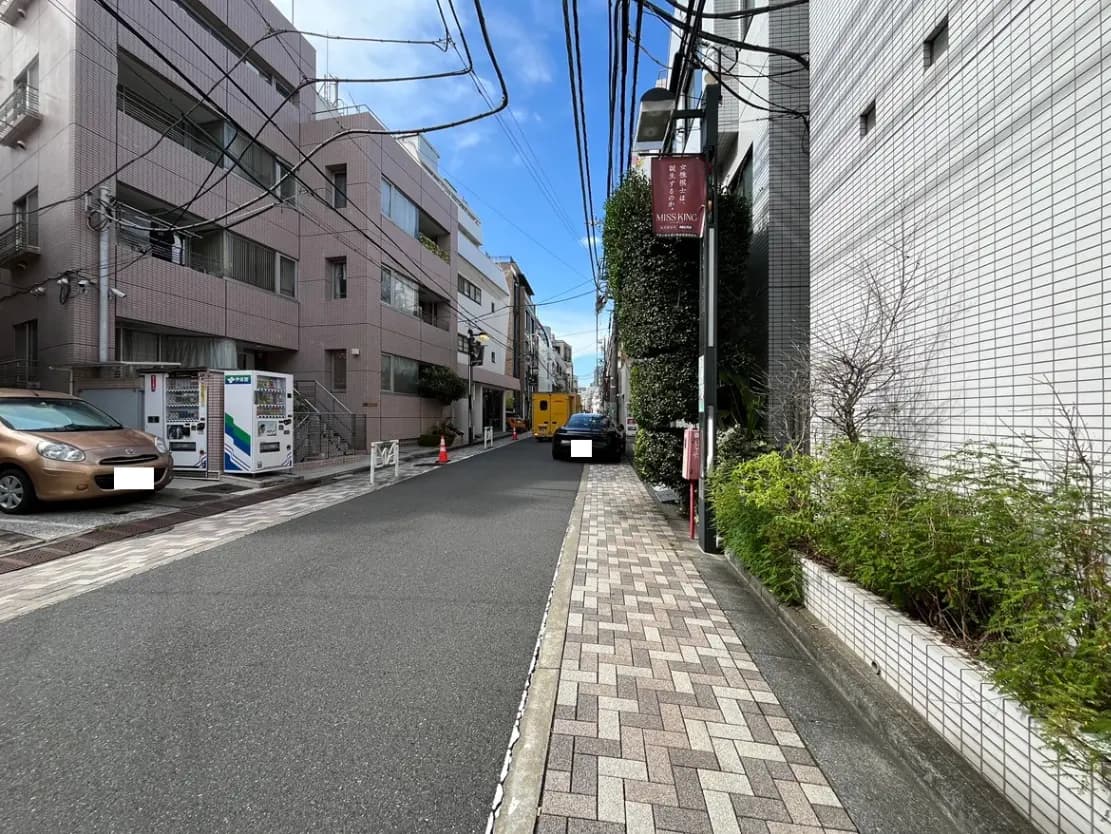 - 都市の住宅街の風景、マンションと並木、舗装された道路、青空に広がる雲のある明るい日中の写真
