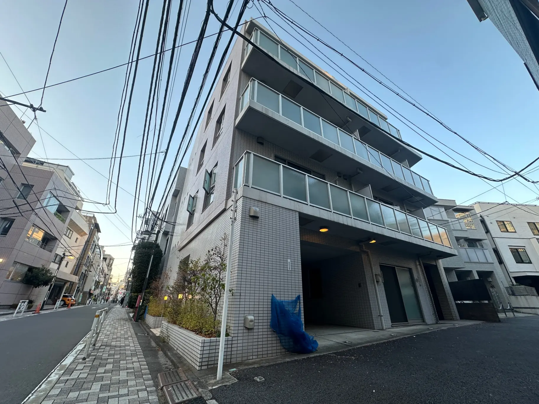 現代的な外観のアパートビル、市街地の舗装された道路、配線が交差する空の景観