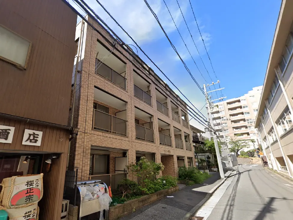 - 住宅街にあるレンガ造りのアパートメント、隣には酒屋があり、青空が広がる通りの風景