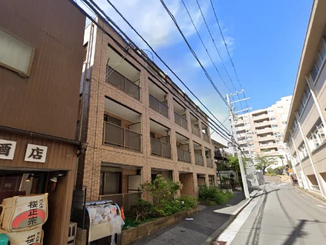 - 住宅街にあるレンガ造りのアパートメント、隣には酒屋があり、青空が広がる通りの風景