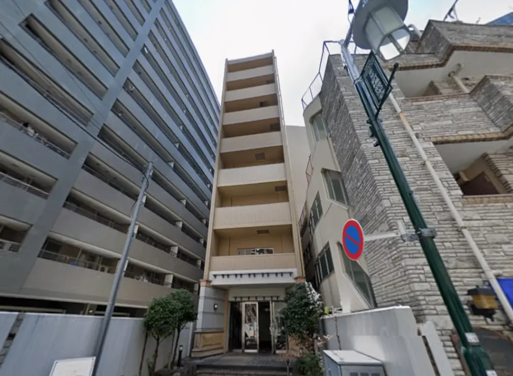 - 高層マンションと隣接する外観、明るいエントランスの階段と緑の植栽がある建物の顔