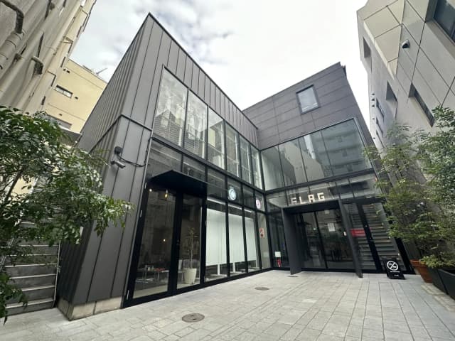 現代的な外観のビル入口、ガラス張りでシックなファサード、植栽付きの都市空間