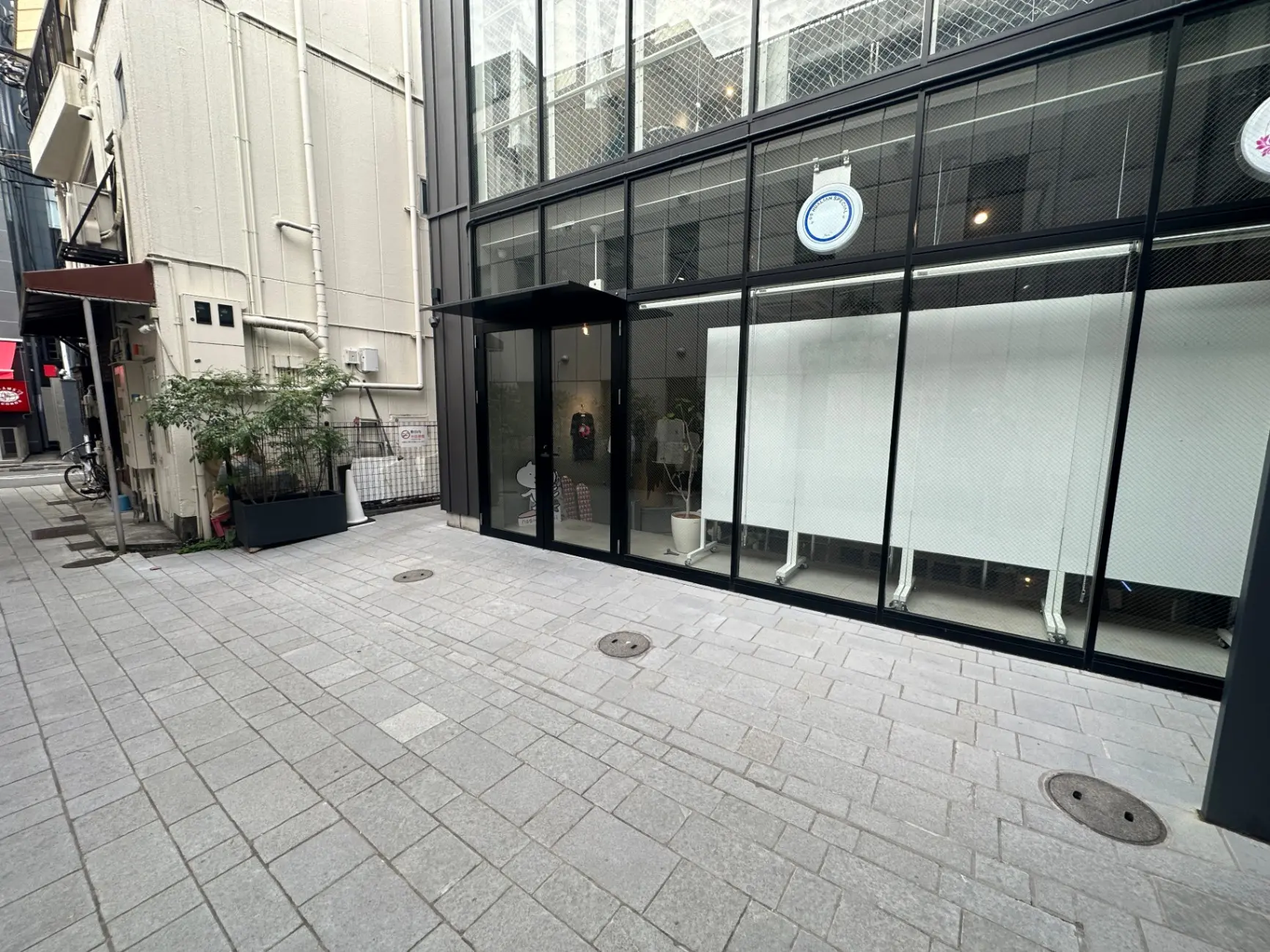 都会の石畳の歩道、モダンなガラス張りの店舗のエントランス、街中の日常風景