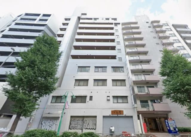 - 都市型マンションの外観、モダンなデザインと緑豊かな街路樹が共存する風景