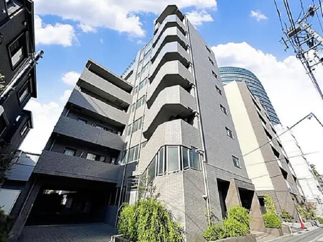 - モダンなデザインのアパートメントビル、灰色のタイル外壁とバルコニー、近代的な都市風景の中に立つ姿