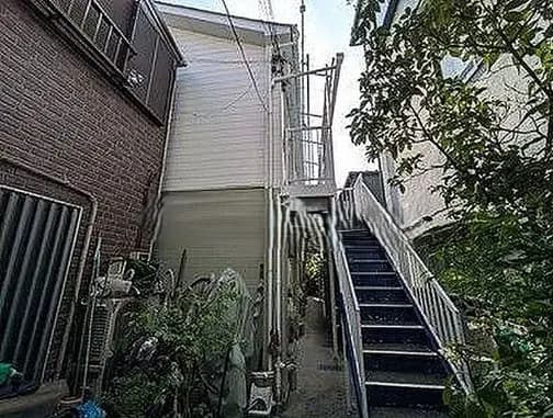 - 階段と隣接する住宅の側面、緑豊かな庭と住宅の外観が見える通路の風景