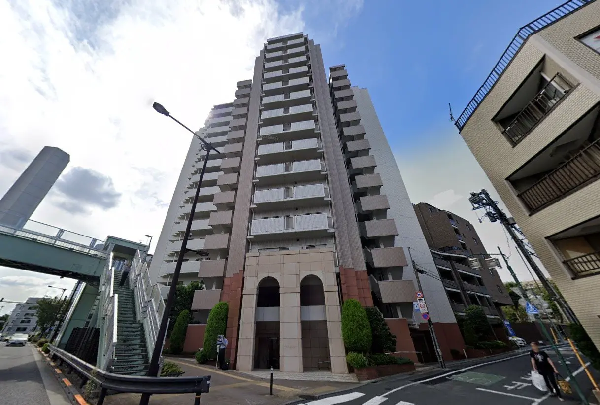 - 現代的なデザインの高層マンション、エントランスに植栽が施され、周囲の街並みと調和した眺め