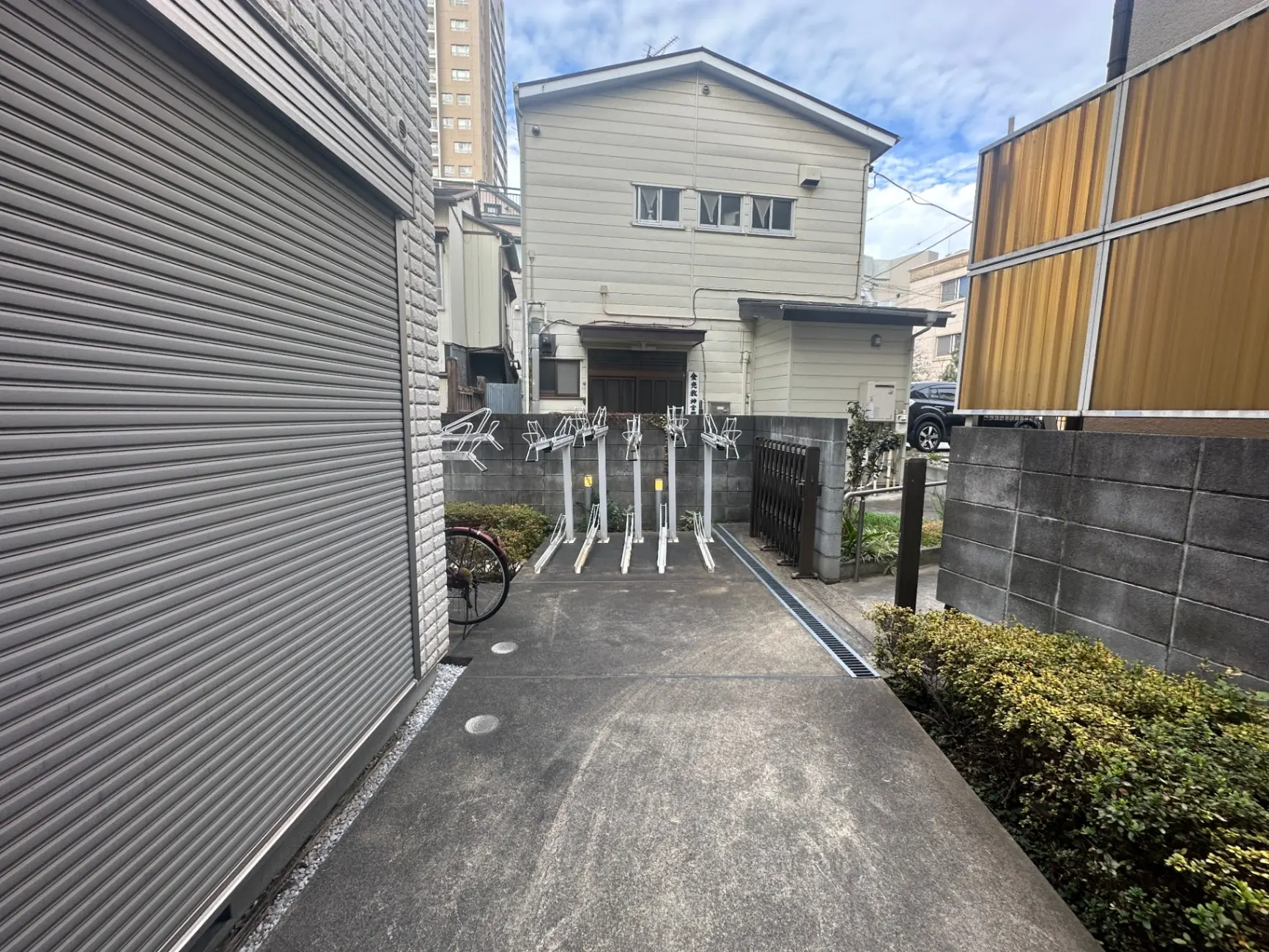 都市の住宅街に位置する門扉と玄関へのアプローチ、自転車が置かれた閑静な通り