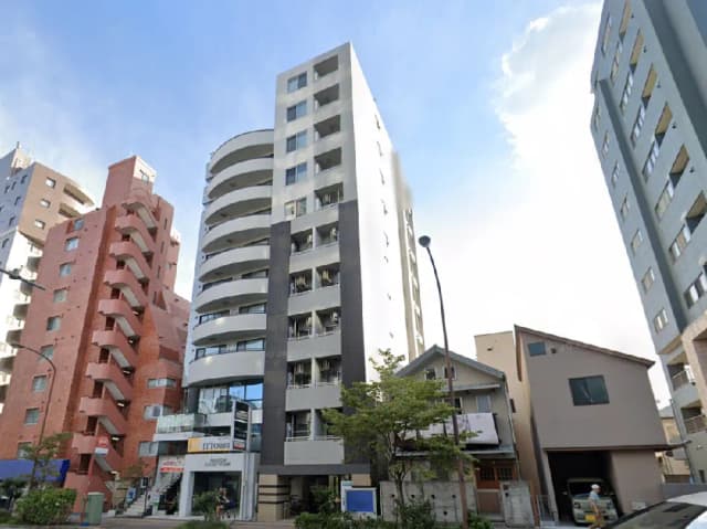 - 栄えた都市に立つ現代的なマンション、隣には赤煉瓦の建物と古民家が並ぶ地域の景観