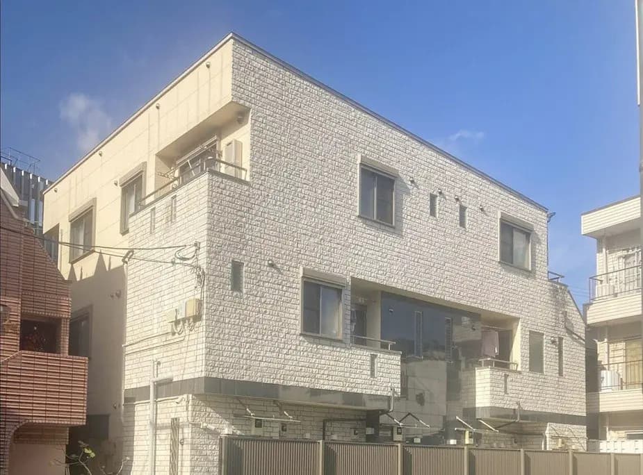 - 近代的なデザインの低層マンション、明るい外壁と大きな窓が特徴、隣接する住宅とのコントラストが印象的な景観