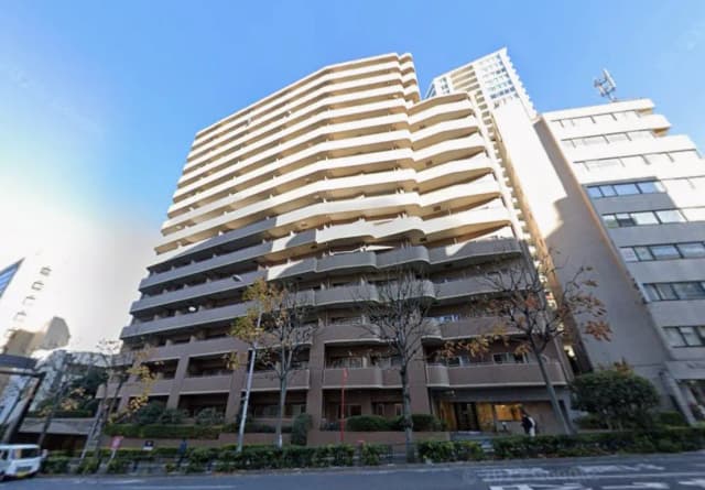 都市の日当たりの良いモダンなマンションビル、幹線道路沿い、樹木が並ぶ歩道