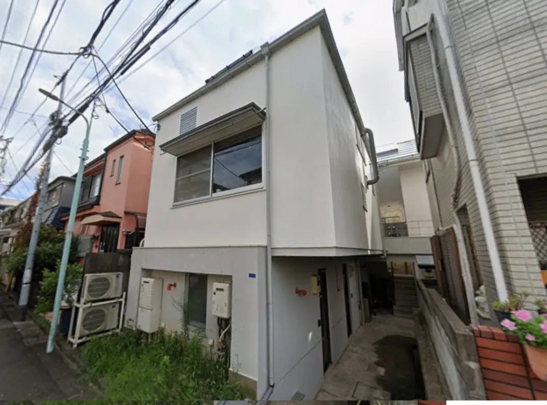 - モダンなデザインの住宅、白い外壁と大きな窓が特徴、隣接する建物との間に通路がある風景