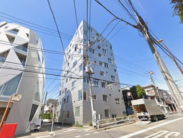 - 近代的なデザインの高層ビルと独特な形状の隣接する建物、青空が広がる街角の風景