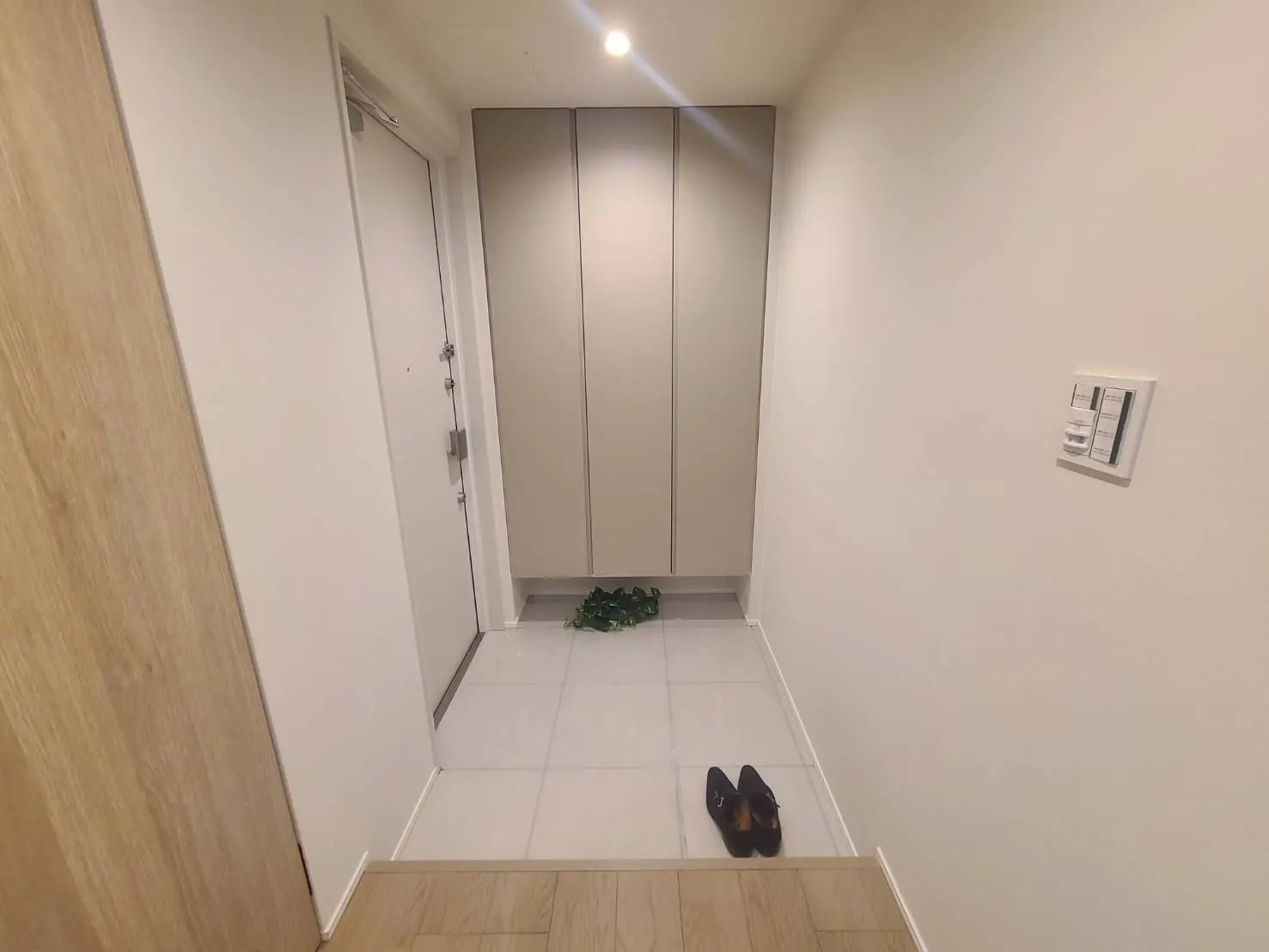 - シンプルで洗練されたエントリーホール、グレーの収納キャビネットと白いタイルの flooring、靴が置かれた空間