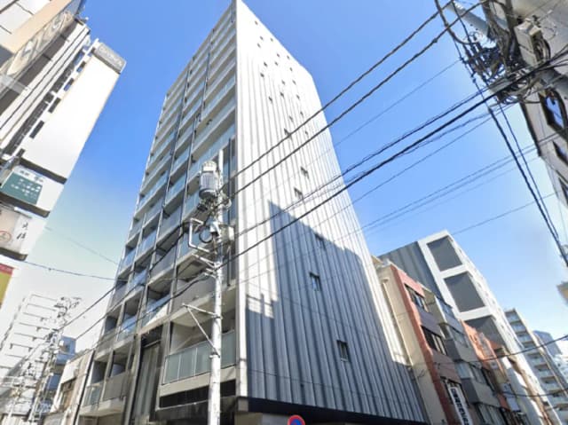 - 現代的なデザインの高層ビル、青空の下での街景色、周囲に並ぶ商業ビルと電線が見える風景