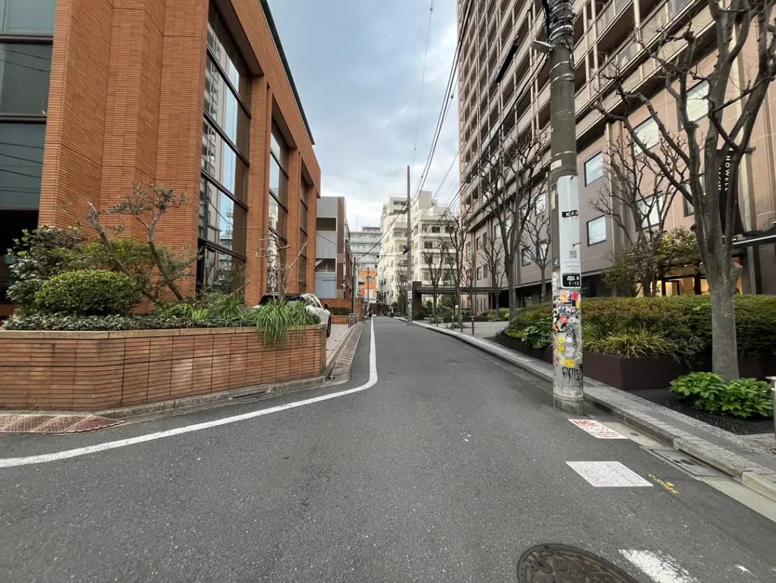 - 都市の街並みを描写した風景、レンガ造りの建物と道路、整備された植栽が特徴的なアクセス道