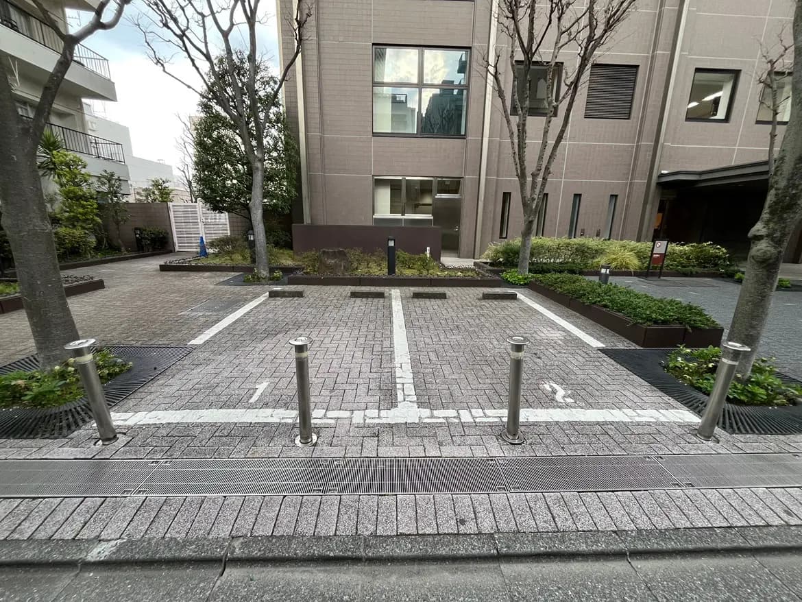 - 敷地内の駐車スペース、整然としたブロックレンガの舗装、周囲には木々と緑の植栽が施された景観
