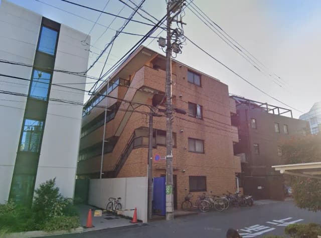 - 複数のアパートメントビルが並ぶ街並み、レンガ調の外観と近代的なデザイン、街灯や電柱が立ち並ぶ様子