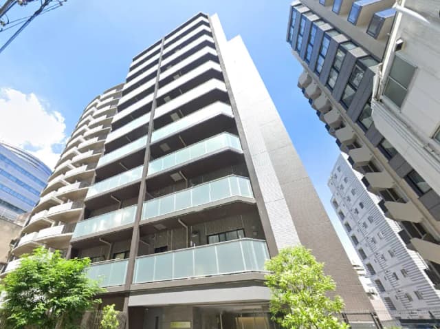 洗練されたモダンなマンションの外観、バルコニーと大きな窓を持つスタイリッシュなデザインのビル、青空を背景にした都市の風景