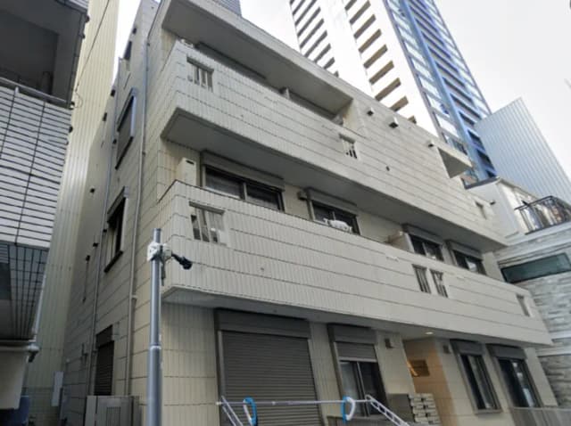 - 現代的なデザインの外観を持つマンション、コンクリート素材のファサードと隣接する高層ビルが立ち並ぶ都市景観