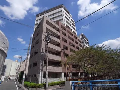 - 現代的なデザインの集合住宅、摩天楼と青い空、周囲に植栽のある街並み