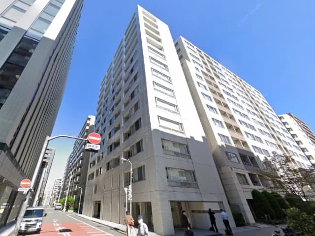 - 高層マンションの外観、青空をバックにした現代的なデザインの建物、周辺にはビジネスマンや通行人が見える街の風景