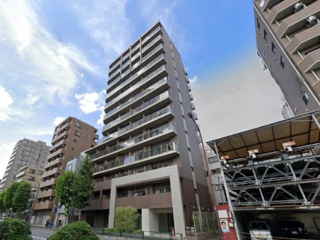- 現代的なデザインの高層マンション、街路樹と周囲の建物が見える都市の風景