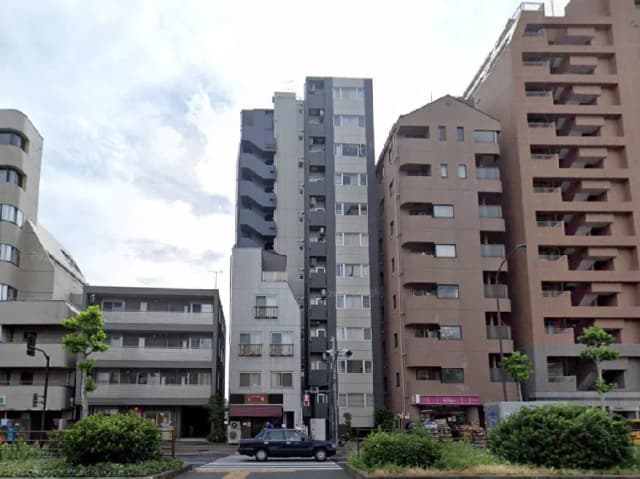 - 都市景観の中に立ち並ぶ様々なデザインのアパートと商業ビル、青空を背景にした街の風景