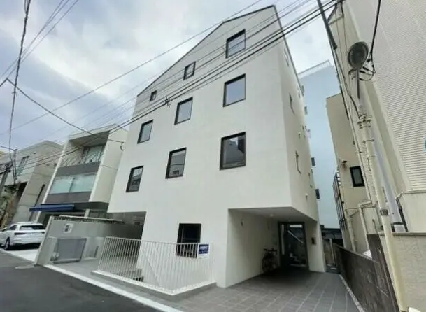 都市の住宅街にある白い外壁の現代的な多世帯住宅、カーポート付き