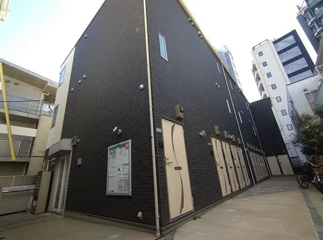 - ブラックの外壁を持つ現代的なアパートメントビル、エントランスと複数の部屋が並ぶ中庭の様子